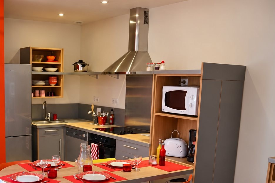 Le coin cuisine équipé : plaques, hotte, four, micro-ondes et rangements en bois.
